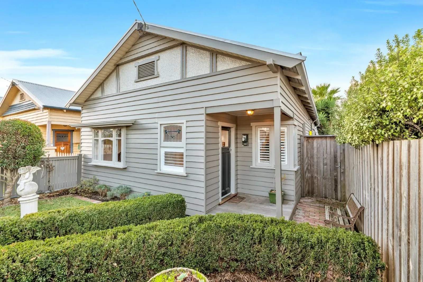 A weatherboard house with a garden and timber fence