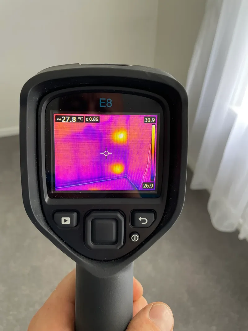 Thermal imaging camera showing heat readings on an interior wall