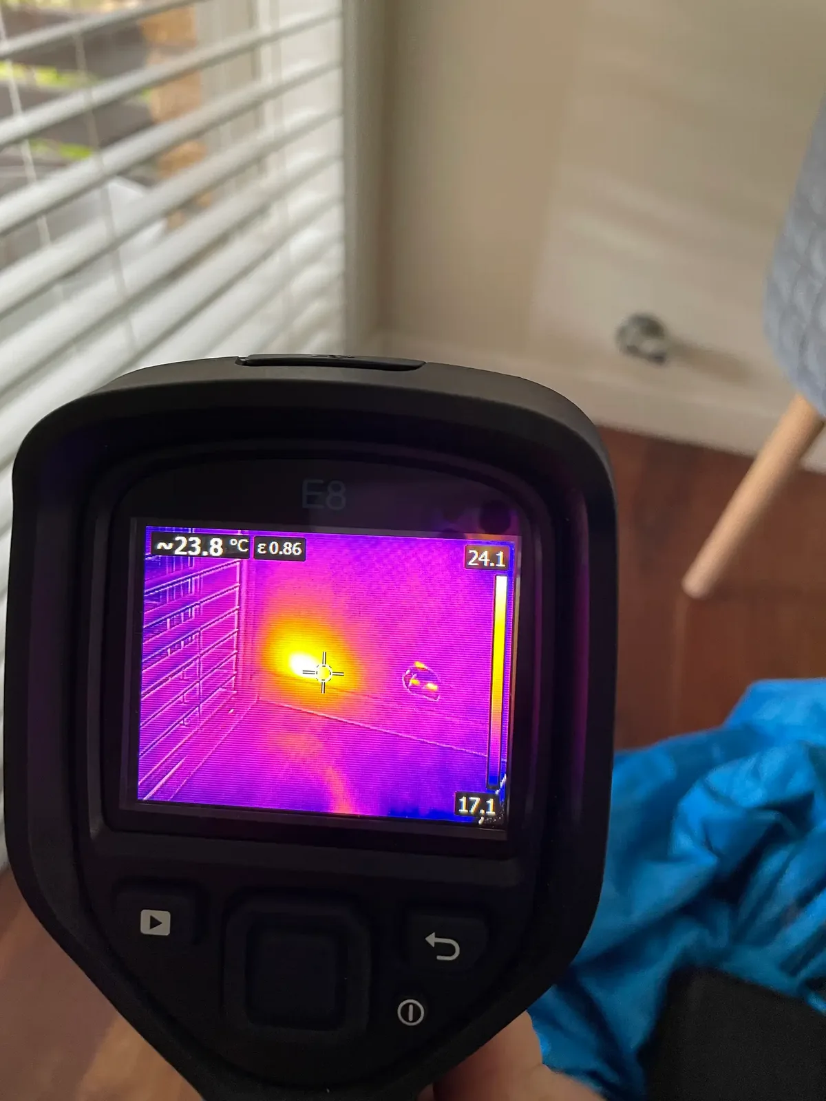 Thermal imaging camera showing a heat map of an interior window and wall during an inspection