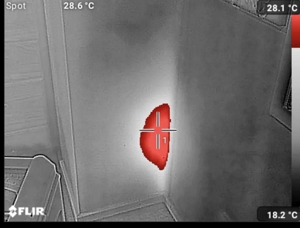 Thermal image of a wall corner with a warm patch marked in red